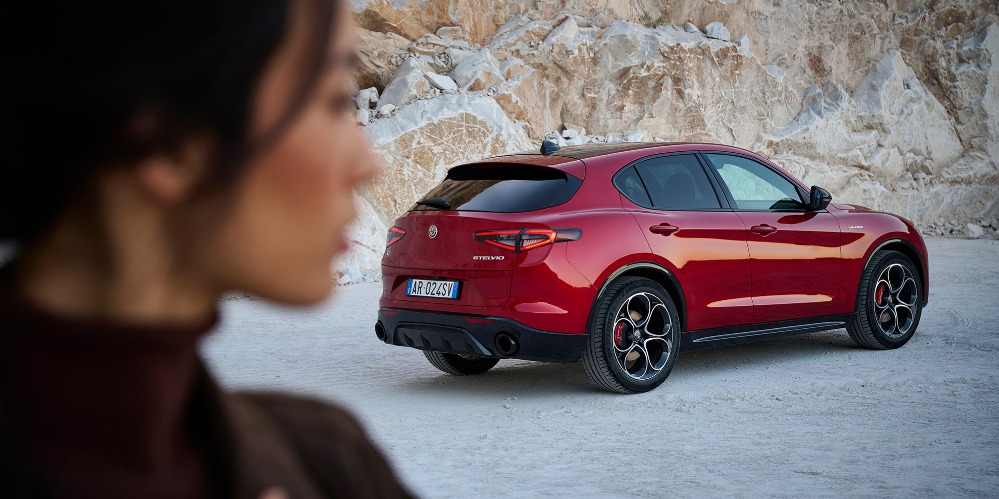 Red Alfa Romeo Stelvio photographed from the rear in a rocky setting.