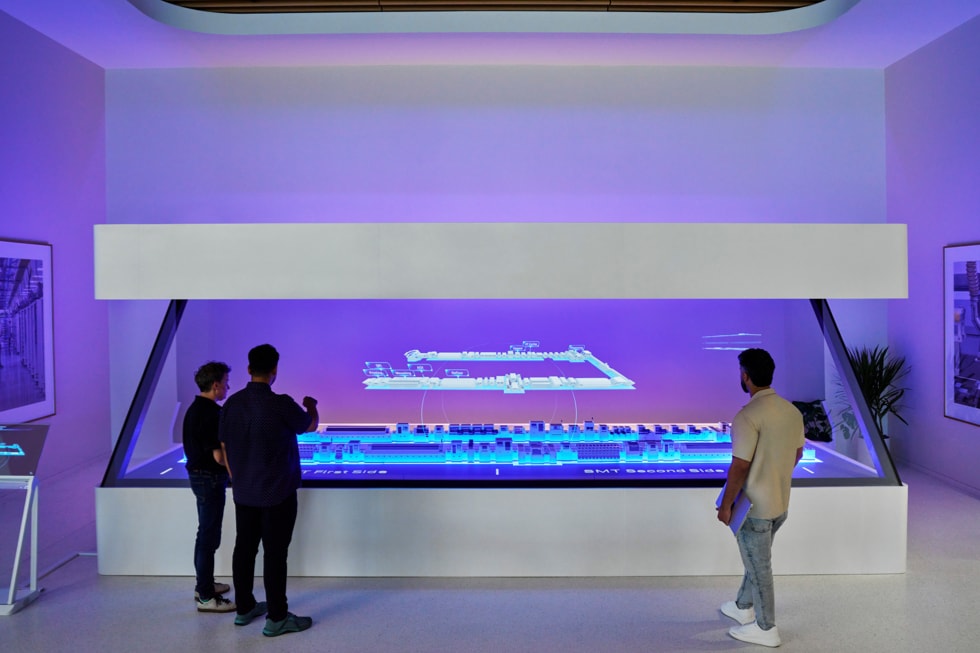 People standing beside a glowing holographic table at Apple's Advanced Manufacturing Center in Houston.