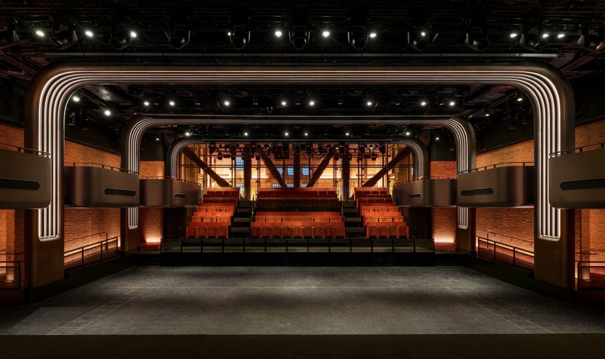 Apple Music Hall’s event space at Battersea Power Station, with a stage, tiered seating and illuminated architectural arches.