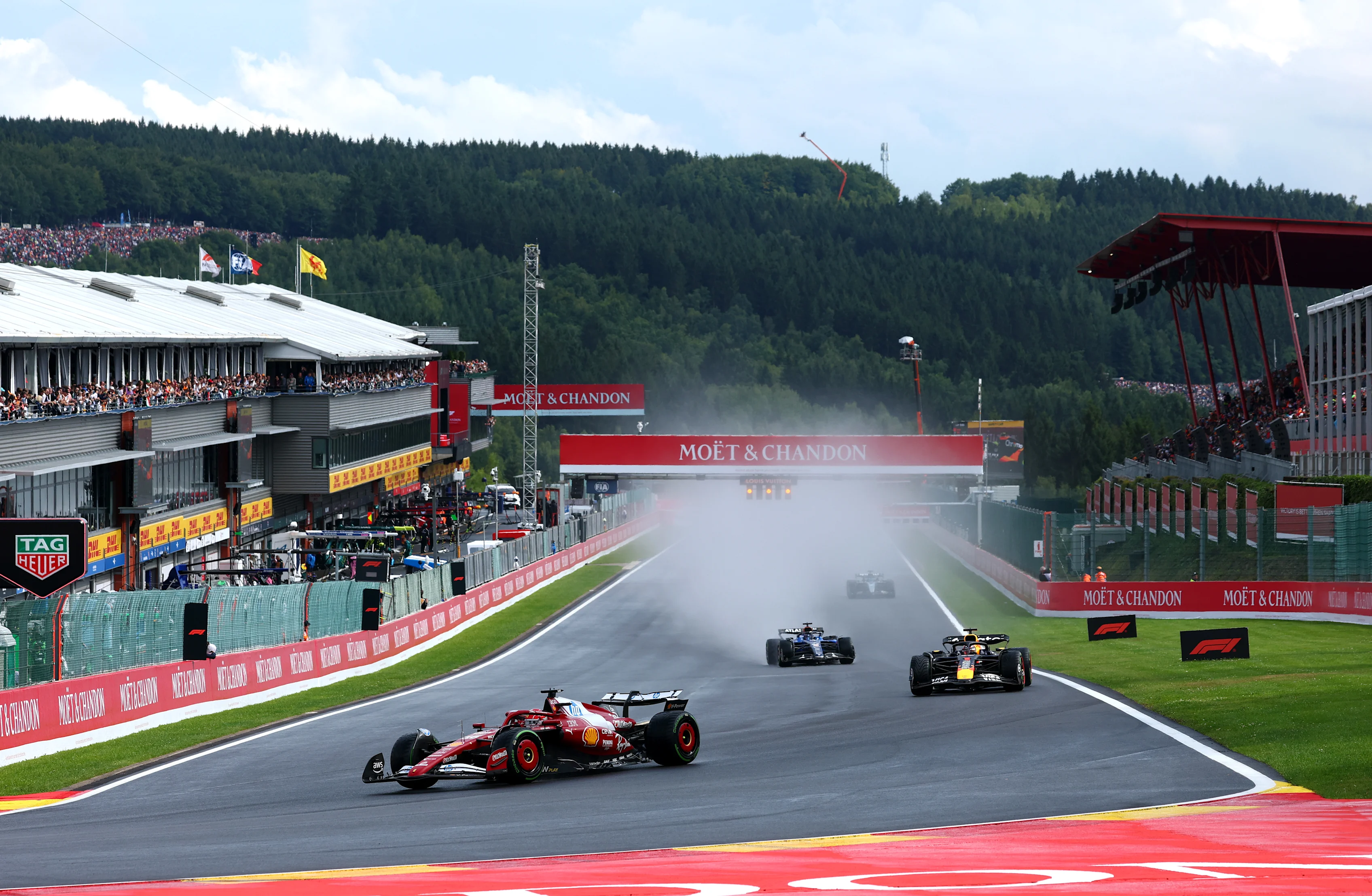 Formula 1 cars running through spray at Spa-Francorchamps.