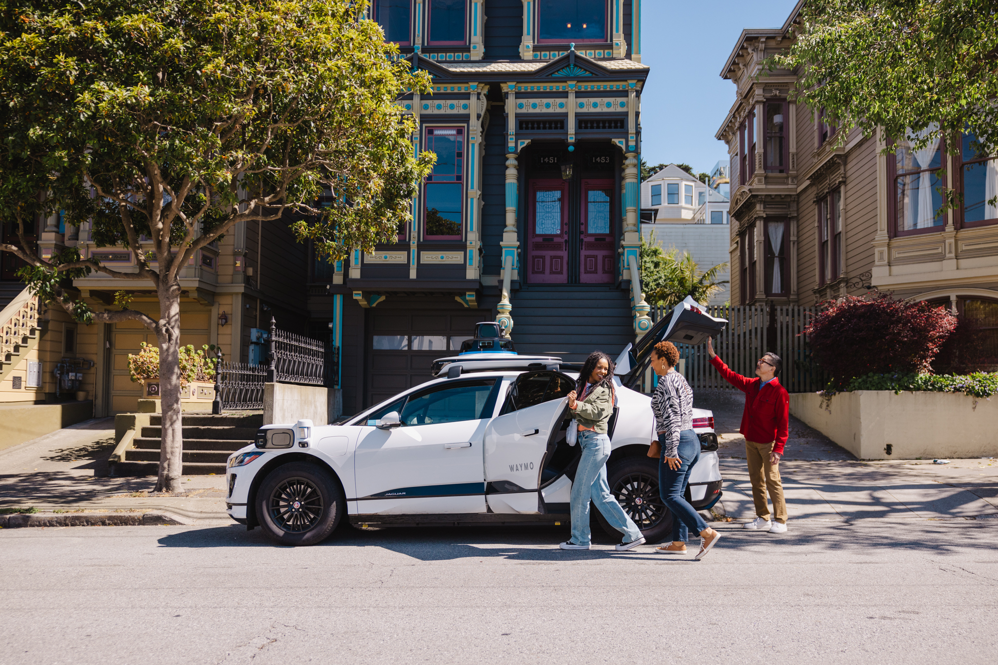 Official Waymo press image showing a Waymo vehicle serving riders in San Francisco.
